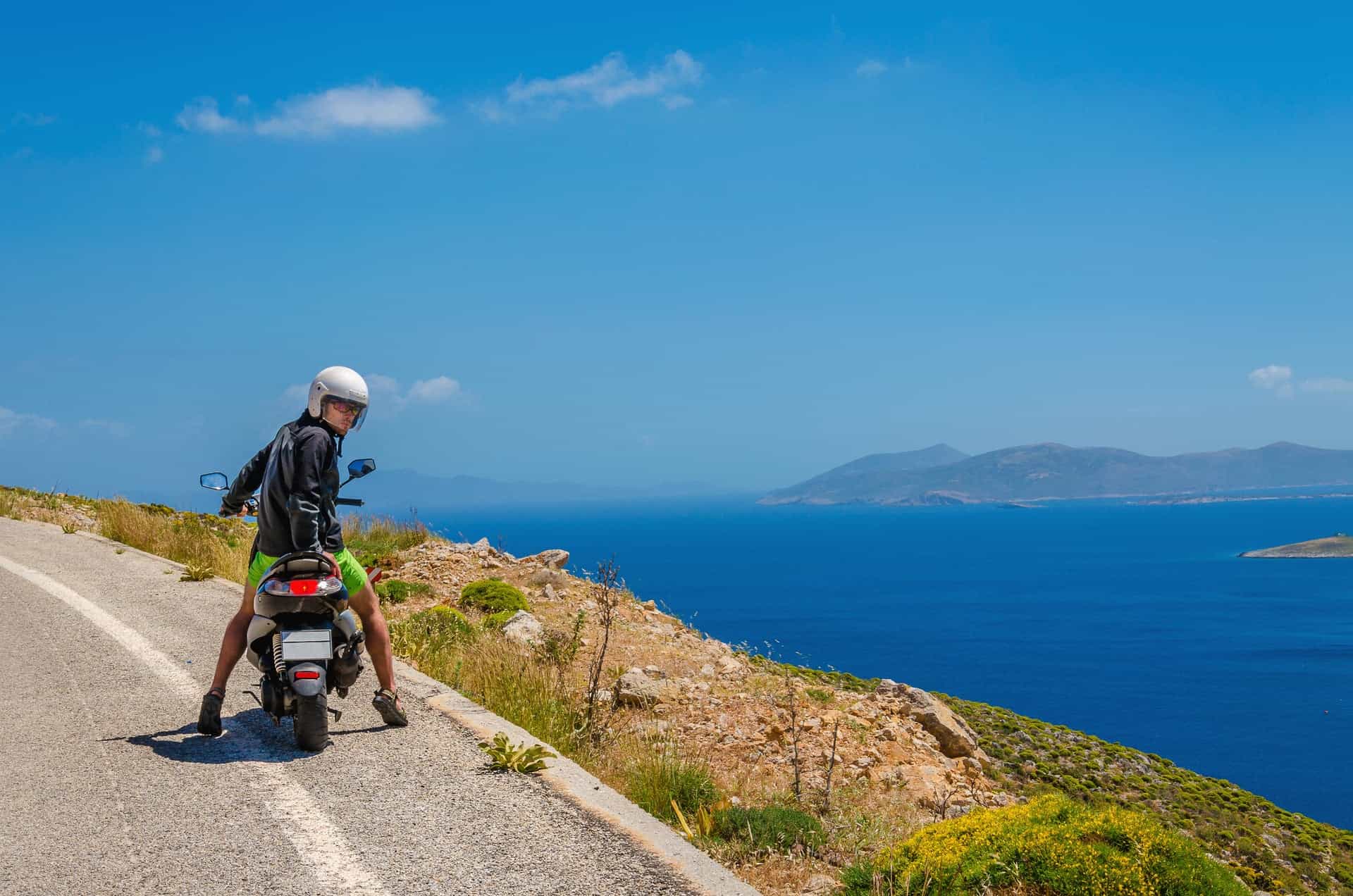 A scooter parked near a golden beach on Paros island, Greece