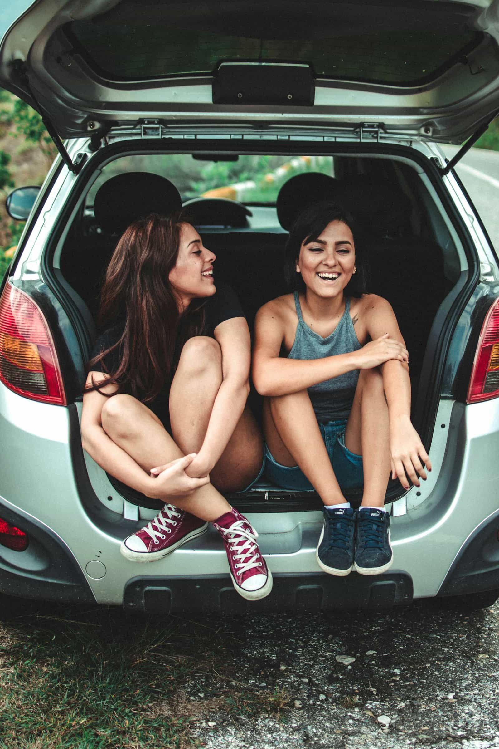 Zwei Frauen sitzen während einer Autoreise in Griechenland im offenen Kofferraum eines Autos