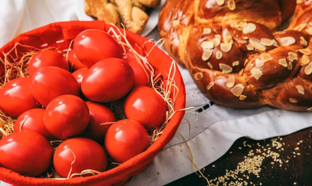 Un panier d'œufs rouges à côté d'un pain sucré de Pâques