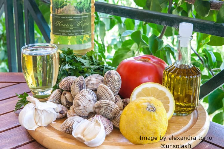 a platter with seafood and herbs to accompany a greek white wine
