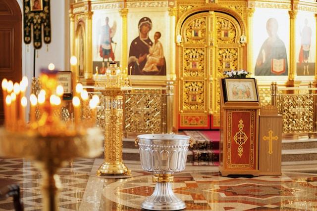 The inside of a greek orthodox church with a candelabra, byzantine frescos and a baptismal font