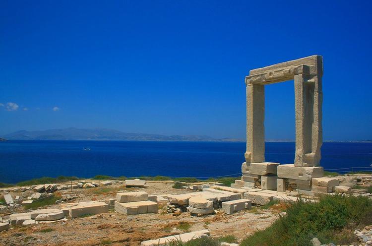 The marble gate of Portara in Naxos, with the Aegean sea and the blue sky on the background