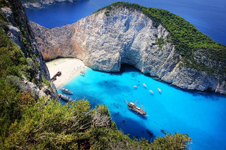 An aerial view of navagio beach, with a shipwreck on its white sand shore and turquoise waters