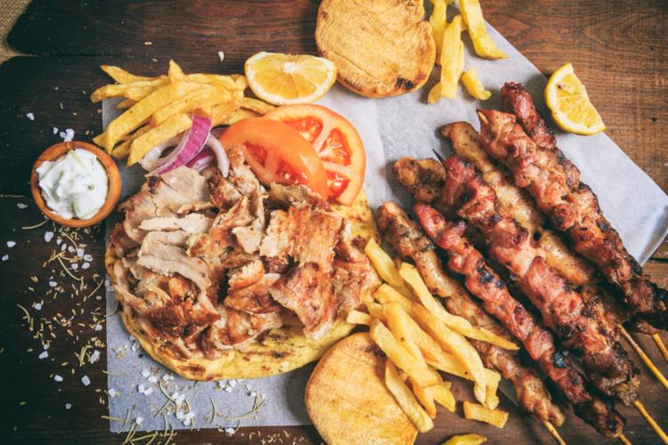 A plater with pittas, gyros, pork & chicken skewers, fries, fresh tomatoes and tzatziki sauce